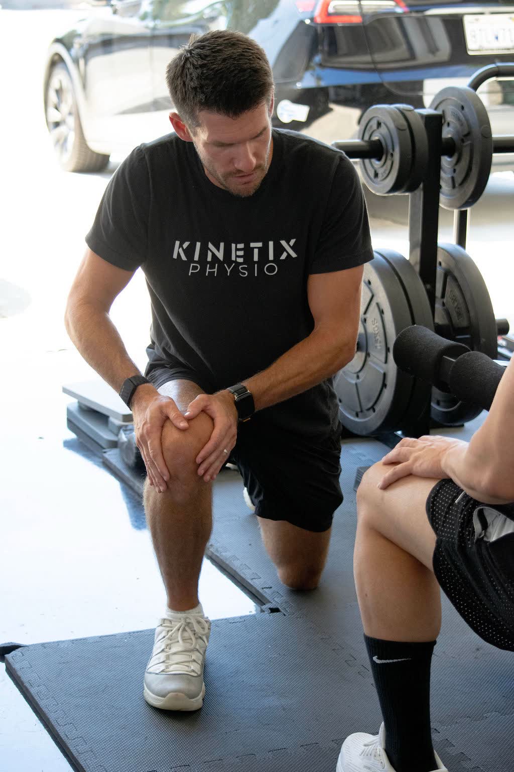 Dr. David of Kinetix Physio assessing a client's knee mechanics during an in-home training session